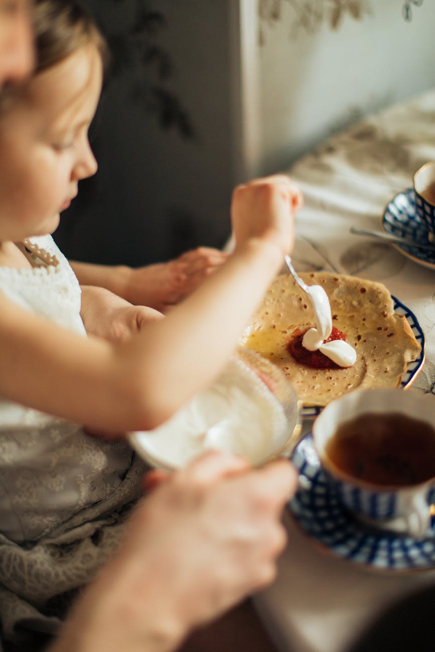 little cute girl spreading jam and cream on crepe